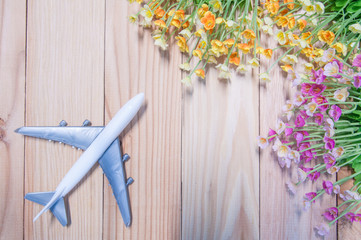 Miniature airplane with artificial flowers on wooden table.