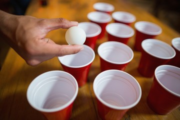 Cropped hand of man playing beer pong