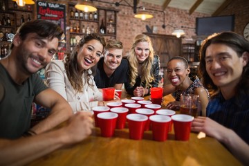 Portrait of smiling friends around disposable cups on table