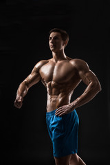 Fototapeta na wymiar Muscular and fit young bodybuilder fitness male model posing over black background.