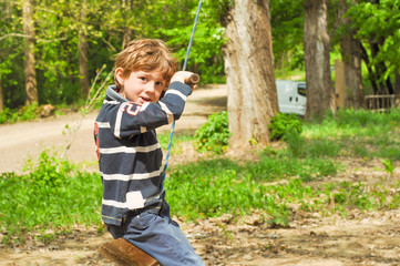 A boy is riding a rope swing