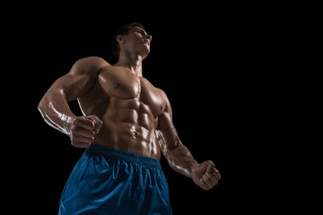 Fototapeta premium Muscular and fit young bodybuilder fitness male model posing over black background.