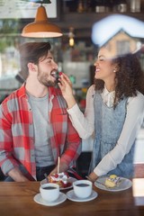 Happy woman feeding cherry to male friend