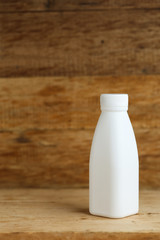 white plastic milk bottles on retro wooden table background