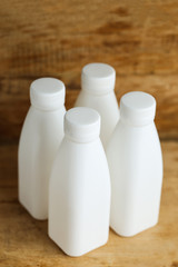 white plastic milk bottles on retro wooden table background