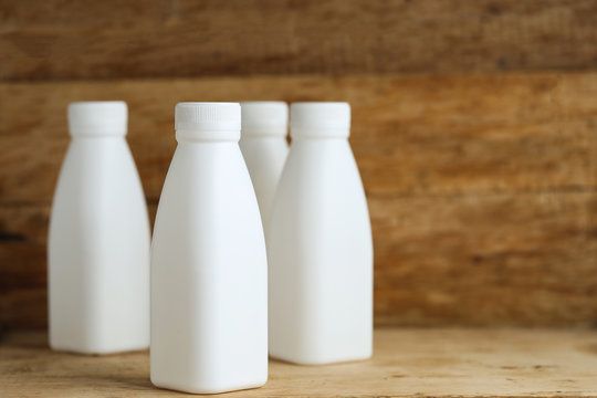 white plastic milk bottles on retro wooden table background