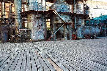 Empty wood floor road surface with old steel steelworks of pipelines