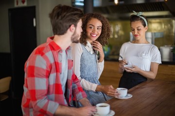 Smiling woman looking at friend while placing order to waitress