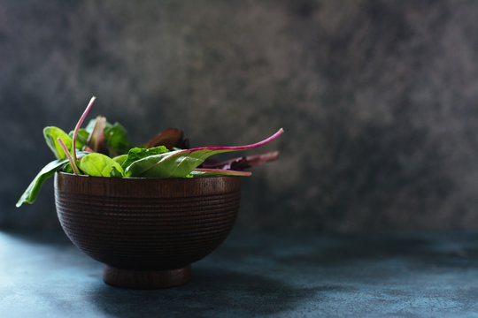 Varieties of lettuce, fresh holas in a wooden bowl over rustic texture