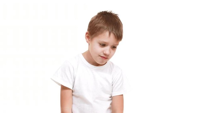 Tired very young Caucasian boy standing faded down on white background