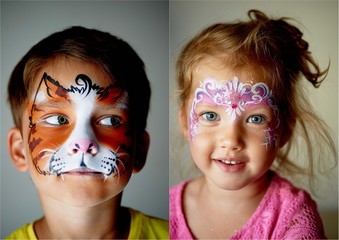 6 years old boy with blue eyes face painting of a cat or tiger.Pretty exciting blue-eyed girl of 2...