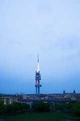 Fototapeta na wymiar Horizon of Zizkov district in Prague, Czech Republic / Czechia - tall Zizkov television communications tower, transmitter and houses. View from Parukarka Park. Dark scenery in the evening.