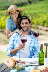 Portrait of happy couple holding red wine at table