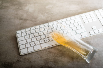 Beer spilled over computer keyboard on concrete table