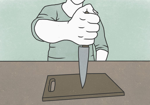 Midsection of man holding kitchen knife on cutting board against colored background