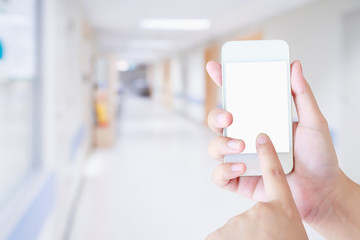 Female hand holding mobile smart phone with blurred hospital background