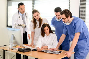 group of surgeons and medical professional staff discussing on patient radiography outside hospital operating room