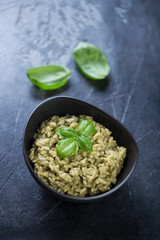 Spinach risotto on a dark grey stone background, elevated view, vertical shot