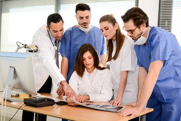 group of surgeons and medical professional staff discussing on patient radiography outside hospital operating room