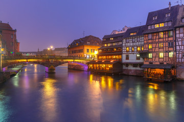 Fototapeta na wymiar Traditional Alsatian half-timbered houses and bridge in Petite France during twilight blue hour, Strasbourg, Alsace, France