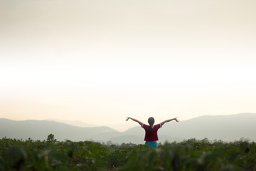 The girl stands in the middle of the mountain while the sun is falling