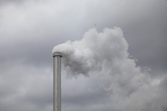 Low angle view of smoke emitting from chimney against cloudy sky