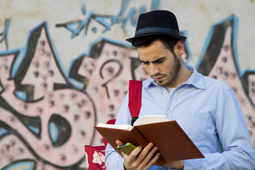 portrait of young man with hat to the urban fashion with the book