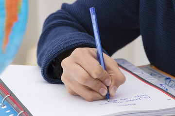 closeup of the hand of the child writing with the pen in the notebook