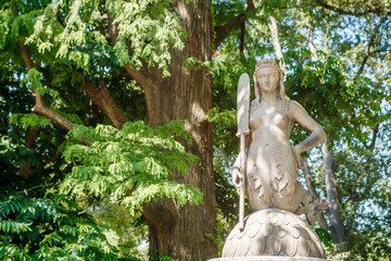 Unknown women mermaid sculpture on trees background in Milano city center park Shiny summer day