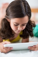 Girl using digital tablet on bed in bedroom