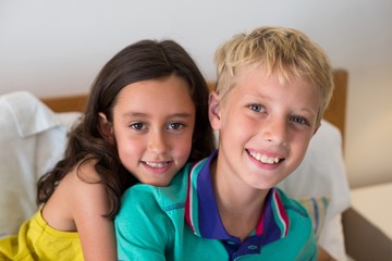 Portrait of siblings embracing each other on bed in bedroom