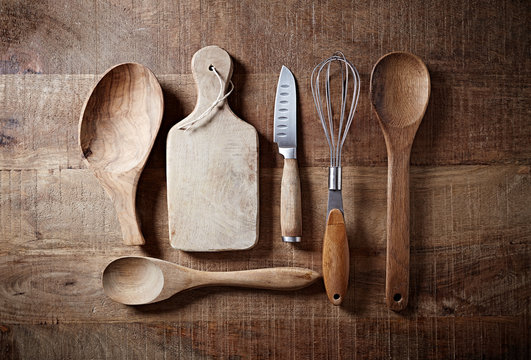 Assorted wooden kitchen utensils on a rustic wooden surface