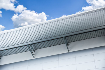 metal sheet factory or warehouse high roof industrial design architecture against of blue cloud sky