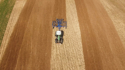 
aerial view of a tractor at work on agricultural fields -  tractor cultivating a field in spring