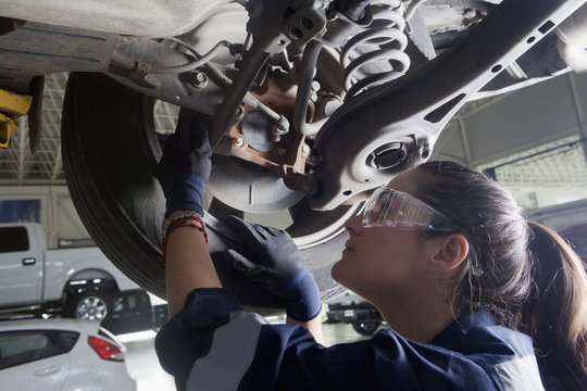 Hispanic mechanic repairing car