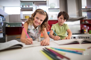 Siblings doing homework in kitchen