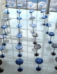 Abstract conceptual composition with many round eating tables staying in empty cafe hall in modern skyscraper vertical view