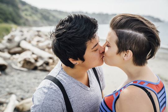 Pregnant lesbian couple kissing on beach