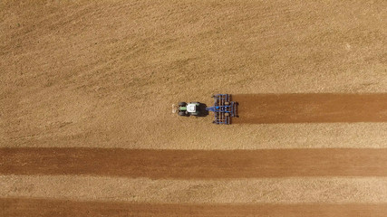 
aerial view of a tractor at work on agricultural fields -  tractor cultivating a field in spring