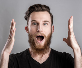 Exited young man isolated on gray background