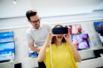 Couple enjoying with VR goggles at tech store. Shopping couple having fun at marketplace.