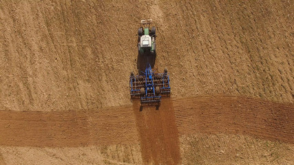 Fototapeta na wymiar aerial view of a tractor at work on agricultural fields - tractor cultivating a field in spring