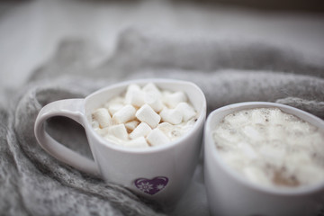 Fototapeta na wymiar two white mugs with marshmallow on the background wool scarf