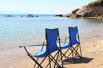 two blue alone chairs on the beach