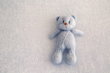 Blue teddy bear knitted toy lies on a blanket
