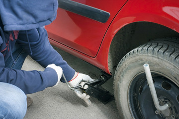 Replacing the broken wheel. Lifting the machine with a jack.