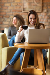 Young woman is working on her laptop in a Caffe on her coffe break
