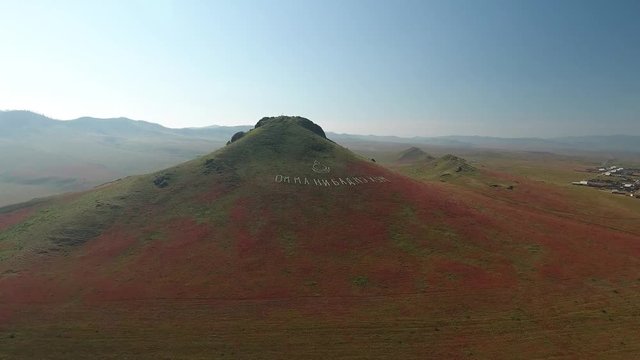 Buddha hill mountain religion sign near Ulan-Ude Buryatia. Road to Ivolginsky Datsan.  Colorful summer weather. Aerial drone flight above