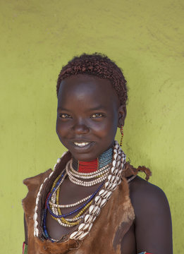 Black girl smiling in traditional clothing against yellow wall