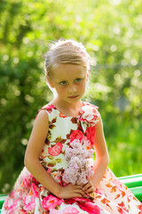 Cute beautiful girl in summer park with bouquet of lilac at sunset in evening